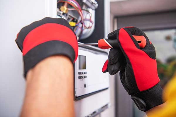 hands in gloves performing furnace repair procedure
